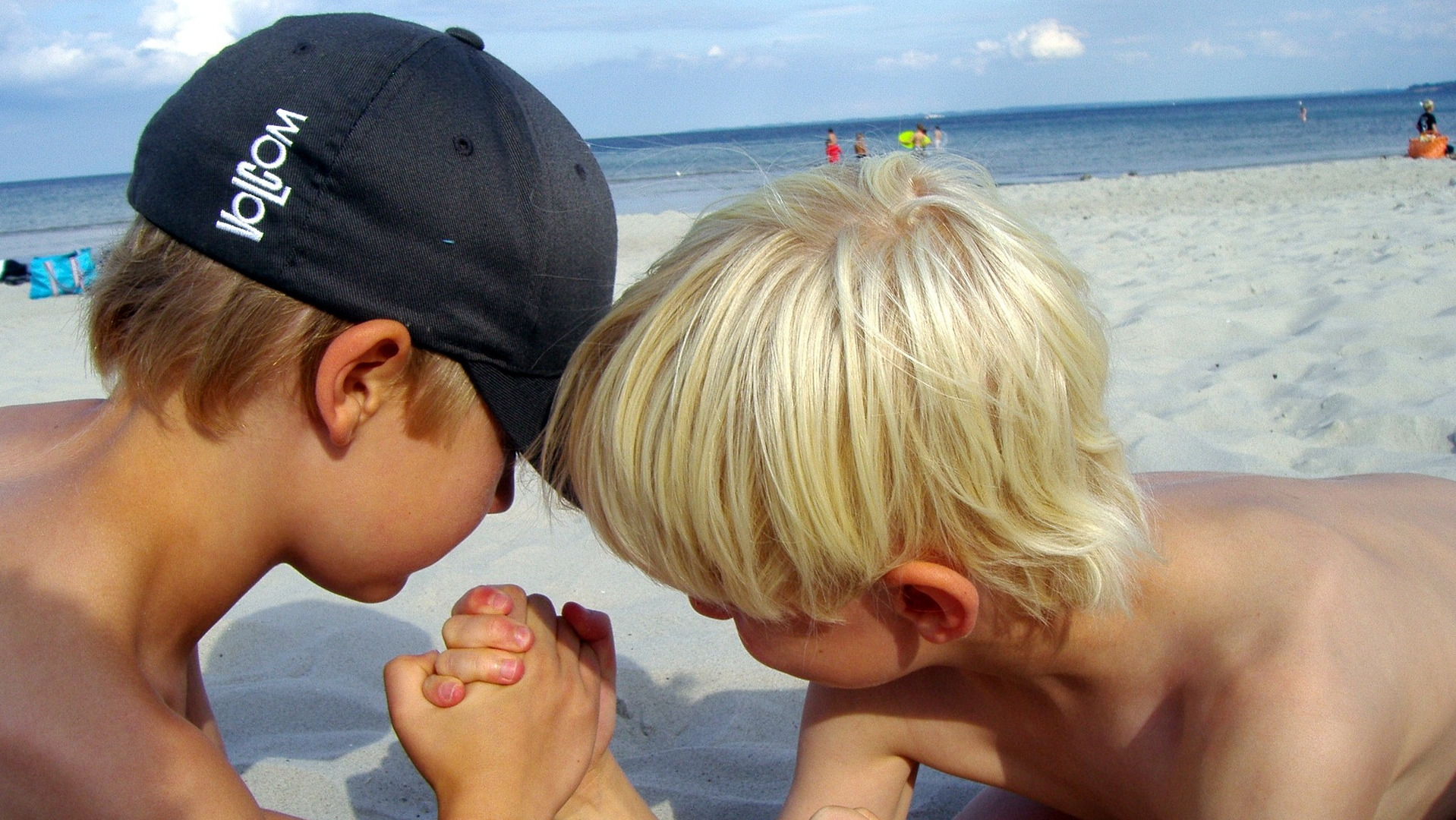 2 young boys arm wrestling on the beach