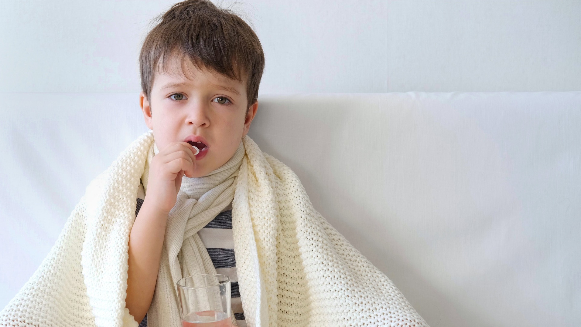 Sick kid in bed taking a tablet