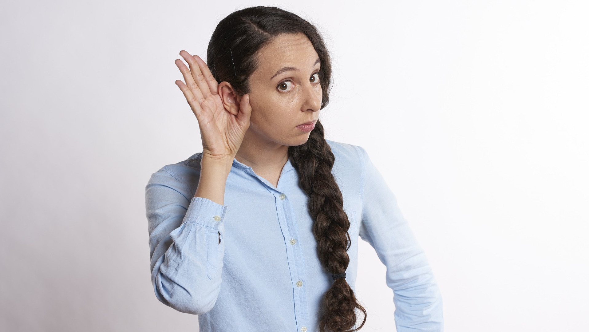 Woman with hand behind ear