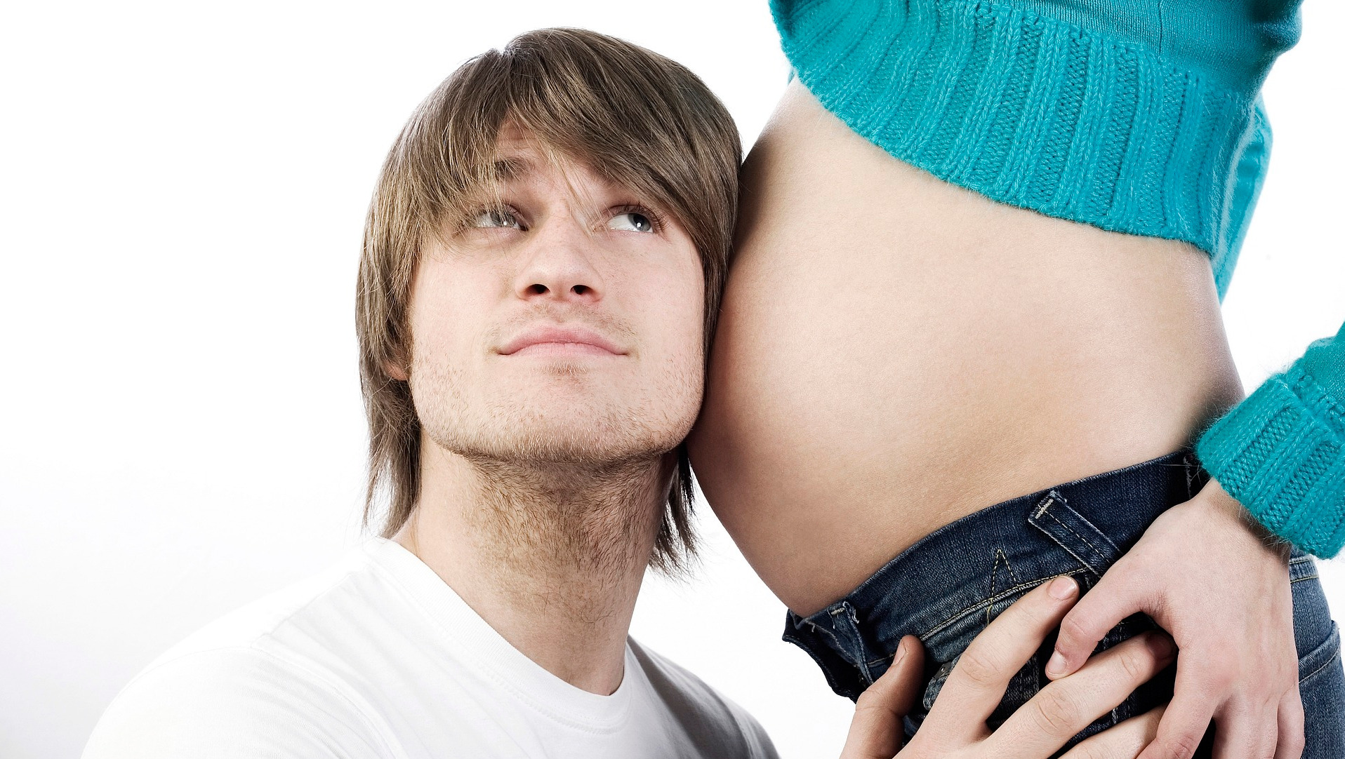 Man with ear to pregnant womans belly