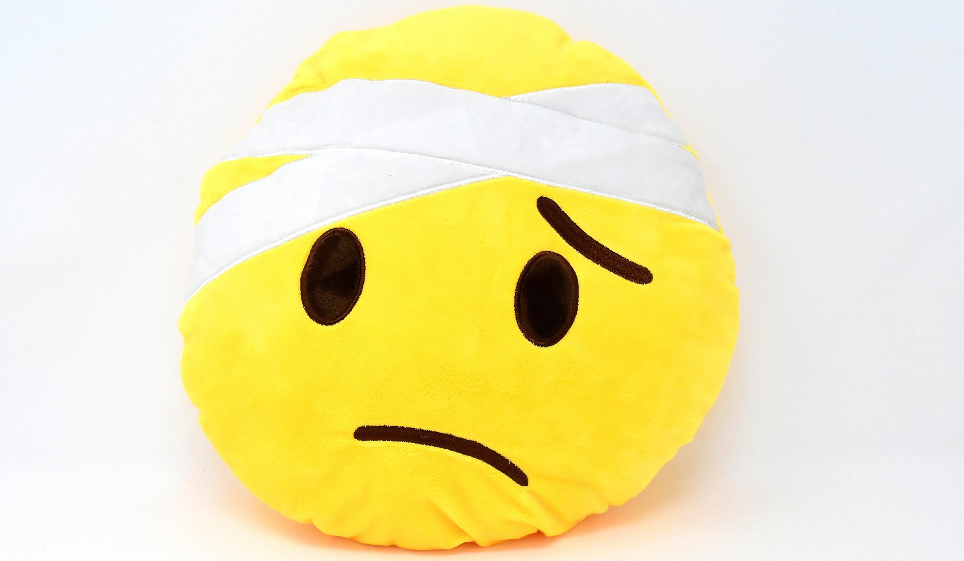 Frowny face pillow with bandaged head