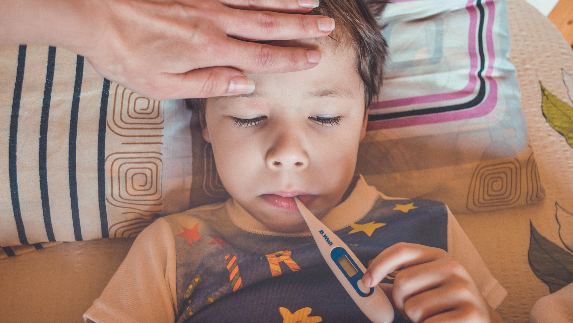 Child sick in bed with a thermometer